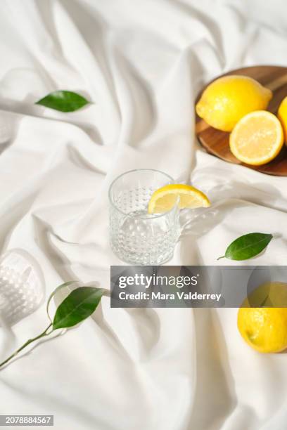 silk wavy white cloth with lemons and a glass with a slice on it - indoor picnic stock pictures, royalty-free photos & images