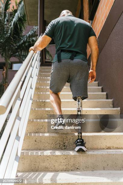 rear view of an unrecognizable man with a prosthetic leg climbing stairs. - wheelchair ramp stock pictures, royalty-free photos & images
