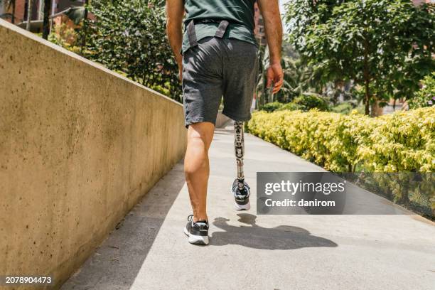 man with prosthetic leg walking in city park. - wheelchair ramp stock pictures, royalty-free photos & images