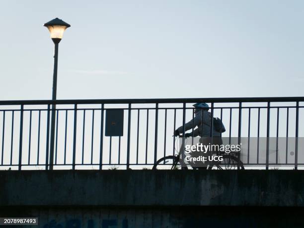 Cyclist on Donnington Bridge, seen from the Thames Path below.