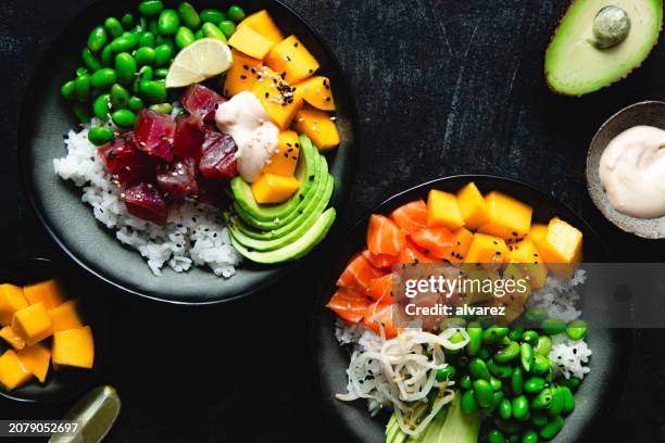 blick aus der vogelperspektive auf die schwarze oberfläche des poke-bowl-salats - asiatische küche stock-fotos und bilder