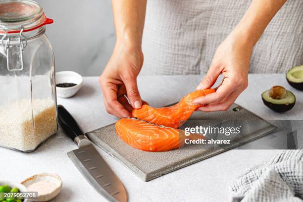 close-up of woman hands placing salmon steak on cutting board on kitchen counter - zalm gerecht stockfoto's en -beelden