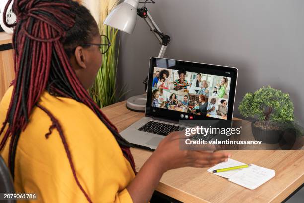 smiling female successful african american woman, wearing bright yellow scarf, sitting at table with laptop, making conference video call with colleagues, family or friends. - flatten the curve imagens e fotografias de stock