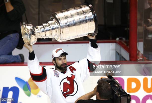 Scott Niedermayer of the New Jersey Devils holds the Stanley Cup over his head on a victory lap after beating the Mighty Ducks of Anaheim in game...
