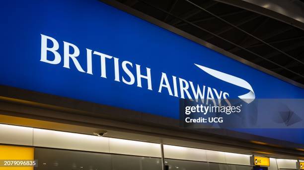 Large blue illuminated logo sign reading "British Airways" in departures at London Heathrow airport Terminal 5, UK.