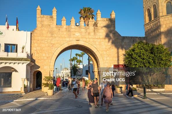 Tourists walk next to an entrance gateway to the marina at Port El Kantaoui in Tunisia.