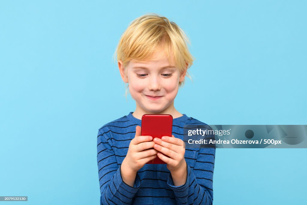 Boy using smart phone against blue background