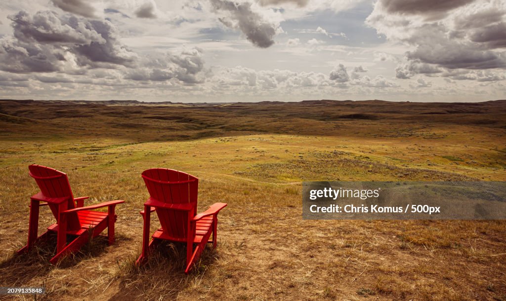 Empty chairs on field against sky