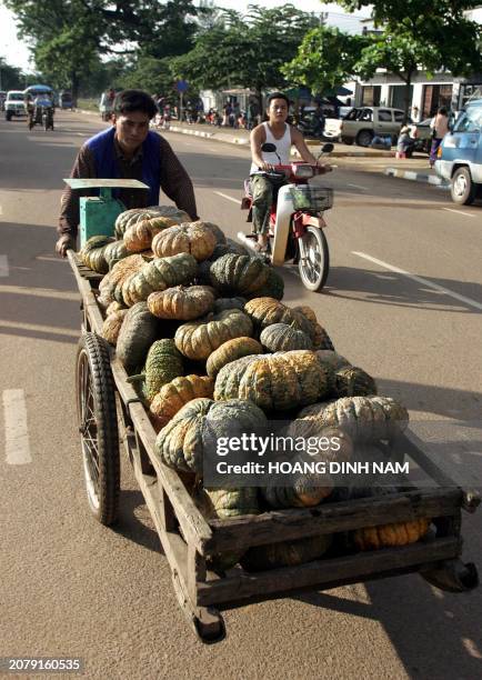 Man pushes a cart loaded with pumpkins for sale along a street in downtown Vientiane 28 July 2005. Laos, one of Asia's poorest countries, is hosting...