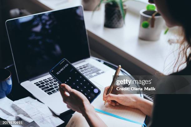 close-up of woman using calculator and laptop for managing home finances - skatt bildbanksfoton och bilder