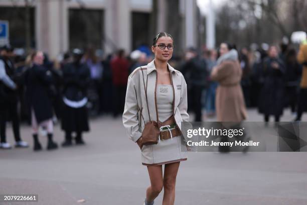 Guest seen wearing Miu Miu hair clips, Miu Miu brown round glasses, Miu Miu beige jacket with brown leather details, Miu Miu strapless top, matching...