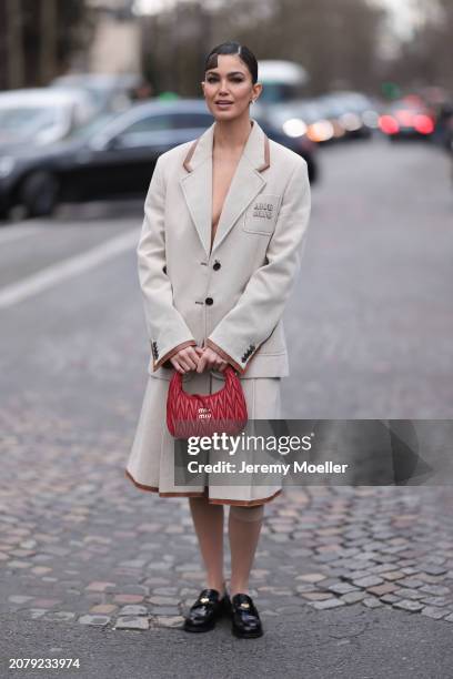 Guest seen wearing Miu Miu beige blazer jacket, Miu Miu matching beige skirt with brown leather details, Miu Miu red leather handbag, brown socks and...