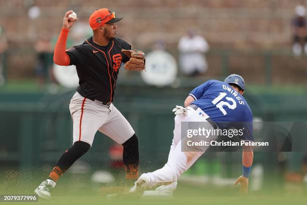 Infielder Thairo Estrada of the San Francisco Giants throws over Chris Owings of the Los Angeles Dodgers after a force out during the third inning of...