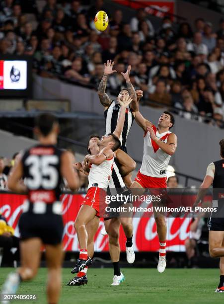 Jamie Elliott of the Magpies attempts a high mark over Lewis Melican of the Swans during the 2024 AFL Round 01 match between the Collingwood Magpies...