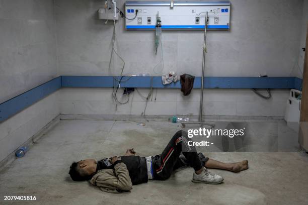 Young Palestinian man injured in Israeli bombardment lies on the ground as he awaits medical attention at the Al-Shifa hospital in Gaza City on March...