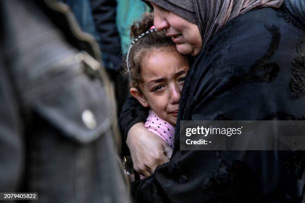 Palestinian woman holds a child as they mourn their relatives killed in Israeli bombardment in front of the morgue of the Al-Shifa hospital in Gaza...