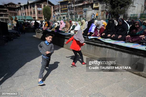 Muslim devotees offer first Friday prayers of the Islamic holy month of Ramadan as children play at the Shah-i-Hamdan shrine in downtown Srinagar on...