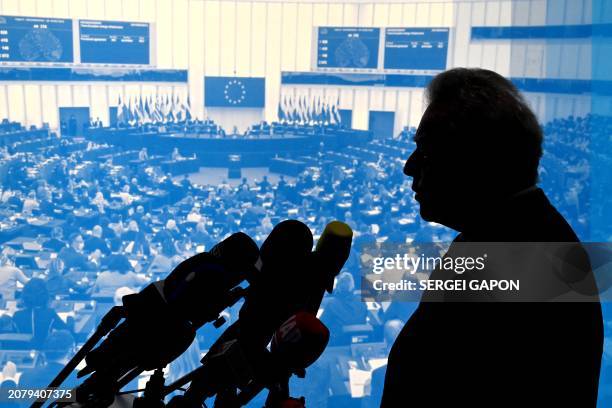 European Commissioner for Agriculture Janusz Wojciechowski is silhouetted against a backdrop showing a European Parliament pleanary as he presents...