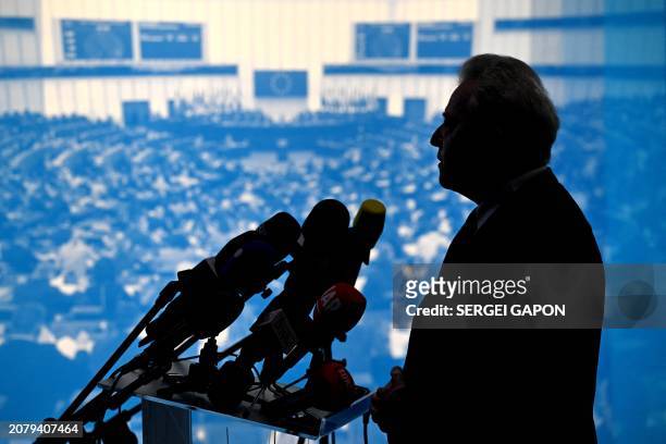 European Commissioner for Agriculture Janusz Wojciechowski is silhouetted against a backdrop showing a European Parliament pleanary as he presents...