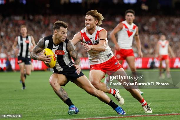 Jamie Elliott of the Magpies attempts to evade Dane Rampe of the Swans during the 2024 AFL Round 01 match between the Collingwood Magpies and the...