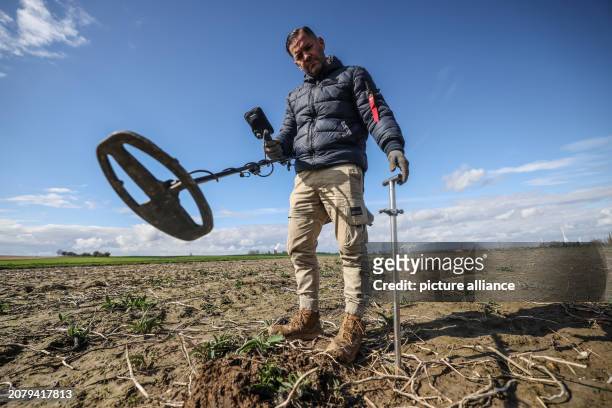 March 2024, North Rhine-Westphalia, Bergheim: Treasure hunter Carsten Konze walks across a field near Fliesteden with a metal detector. Photo: Oliver...