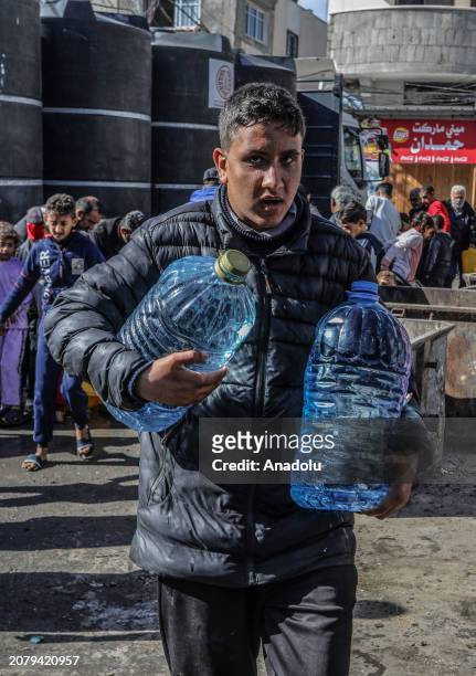 Palestinians carry and fill up the water bottles amid clean water and food crisis from mobile storages of charities as they have limited access to...