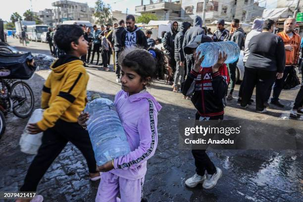 Palestinians carry and fill up the water bottles amid clean water and food crisis from mobile storages of charities as they have limited access to...