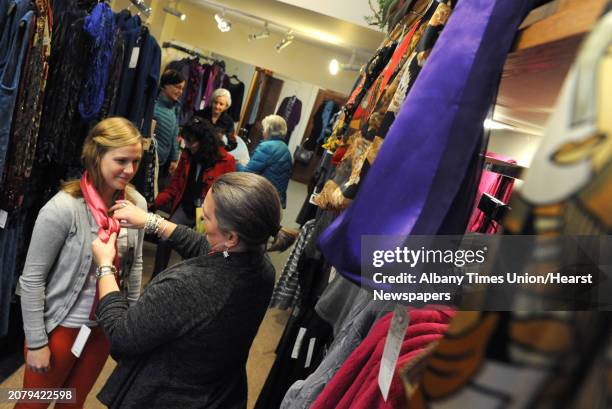 Silver Parrot manager Christie Waldman, center, ties a scarf on Melissa Miller of Latham during small business Saturday at Stuyvesant Plaza on...