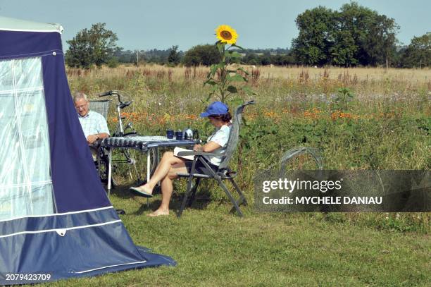 Couple sits near their tent as they camp at an organic farm on August 10, 2009 in Vaux-sur-Aure, western France. AFP PHOTO MYCHELE DANIAU