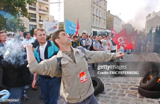 Des salariés de l'usine Philips du Mans jettent des pétards devant les grilles du siège Philips, le 12 octobre 2001 à Suresnes. Les manifestants...