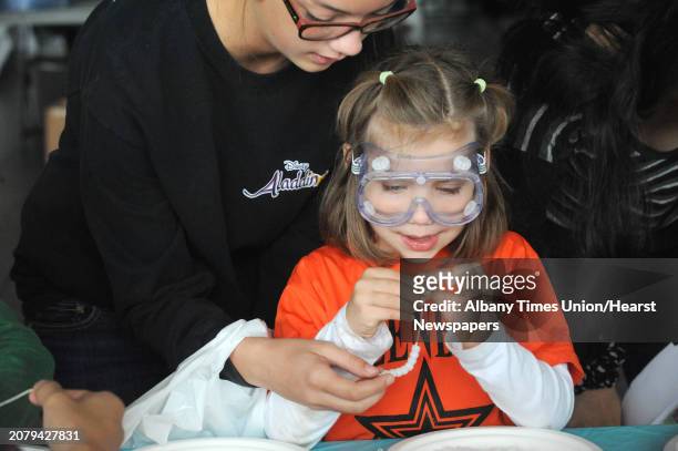 Five-year-old Brooke Haney, center, and her older sister Rachel Haney work on a ulta violet light experiment at the Skidmore College Shem Club...