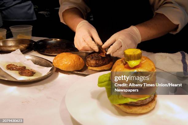 Sous chef Trevor Gaughan plates a dp burger made with ground wagyu beef, shaved truffles, seared Hudson Valley foie gras, applewood smoked bacon,...