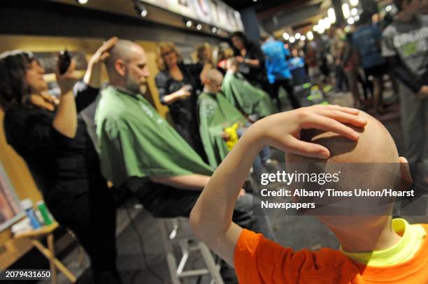 Seven-year-old Stephen Waldin, right, of Ballston Spa rubs his head after it was shaved as he watches his father Jeffrey Waldin do the same during...