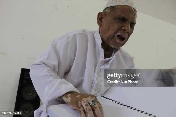 An elderly Muslim man with special needs, who is also blind, is reading the Koran in Braille at the Medan Center for the Blind during the holy month...