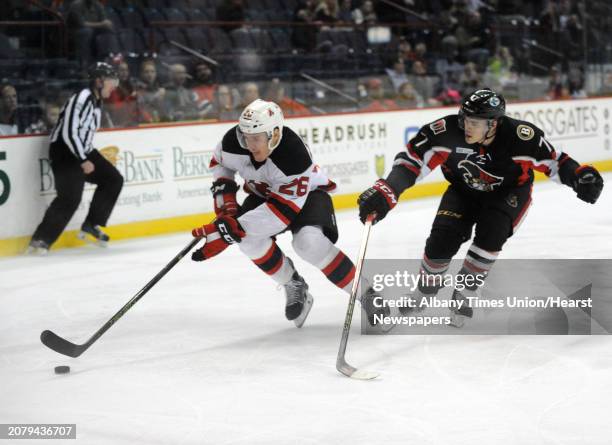 Devil Ben Thomson and Binghamton's Chris Carlisle go after the puck during their hockey game at the Times Union Center on Wednesday April 13, 2016 in...