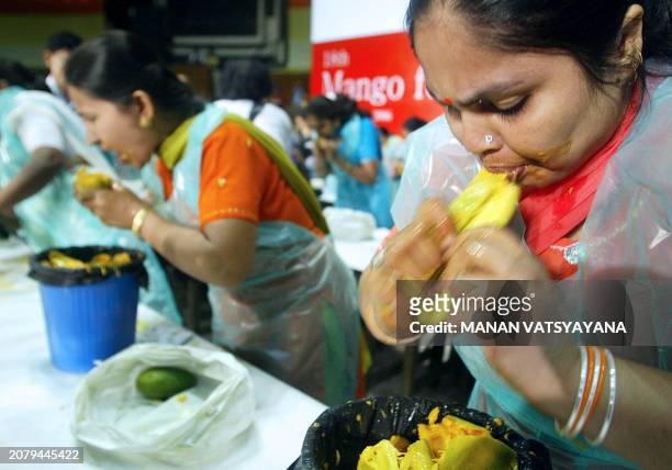 Indian women take part in a mango-eating contest at the 18th Annual Mango Festival in New Delhi, 08 July 2006. The two-day festival showcases some...