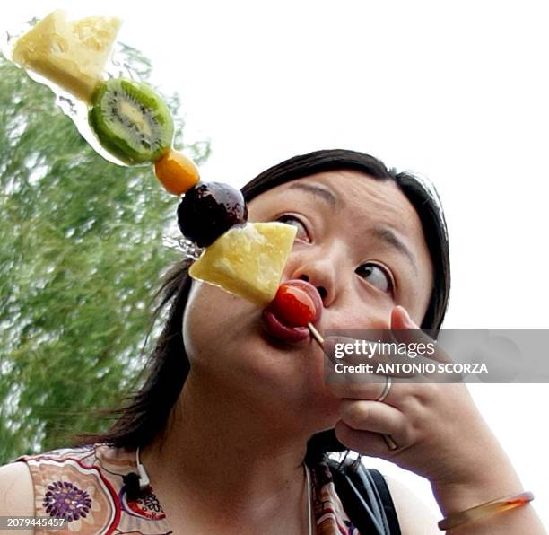 Woman eats fruits on a street of Beijing, on August 6, 2008. The 2008 Beijing Olympic games will take place between August 8 and 24. AFP PHOTO...