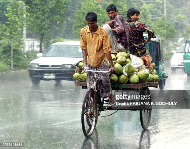 Bangladesh rickshaw driver makes his way with passengers through a heavy down pour in Dhaka, 06 July 2006. Heavy rain disrupted life in the...