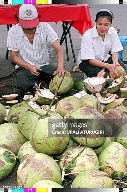Vendor cuts a young coconut for a Moslem girl who is preparing for the break of her fasting 30 January. Young coconut water, costing one dollar each,...