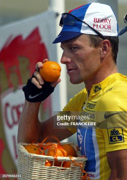 Lance Armstrong takes an orange from his basket after he received the Orange prize from the photograhers which rewards the nicest rider before the...