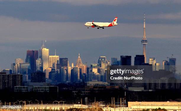 Plane is arriving at Toronto Pearson International Airport while the sun is setting on downtown Toronto. This view is captured from the Final...