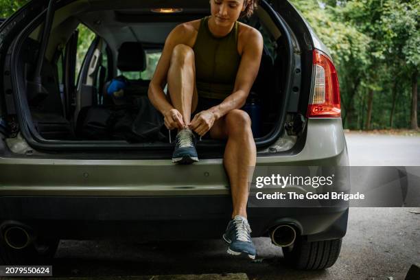 woman sitting in car trunk while tying shoelace before run - mazda stock pictures, royalty-free photos & images