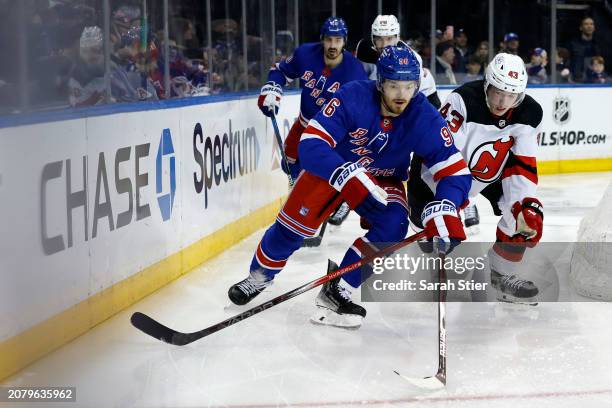 Jack Roslovic of the New York Rangers skates with the puck against Luke Hughes of the New Jersey Devils during the second period at Madison Square...