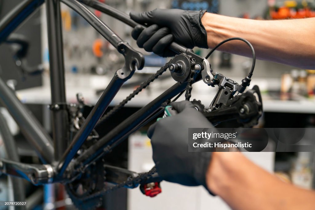 Nahaufnahme eines Mechanikers, der eine Fahrradkette in einer Werkstatt repariert