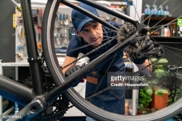 mechanic fixing a bicycle at a repair shop - hispanolistic stockfoto's en -beelden