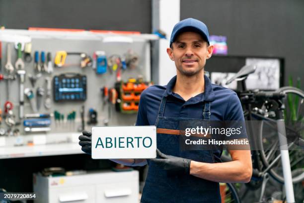 mecánico de bicicletas con un cartel abierto en un taller de reparación - hispanolistic fotografías e imágenes de stock