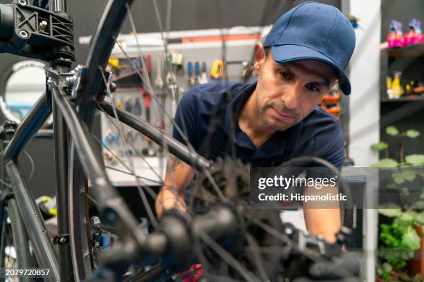 mecánico de bicicletas que trabaja en un taller de reparación arreglando una bicicleta - hispanolistic fotografías e imágenes de stock