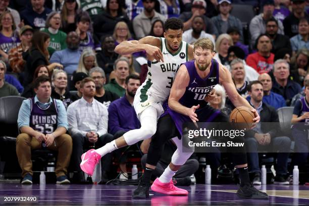 Domantas Sabonis of the Sacramento Kings is guarded by Giannis Antetokounmpo of the Milwaukee Bucks at Golden 1 Center on March 12, 2024 in...