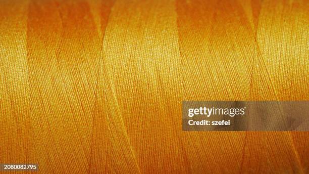 close-up view of gold color string spool - linhas texteis imagens e fotografias de stock