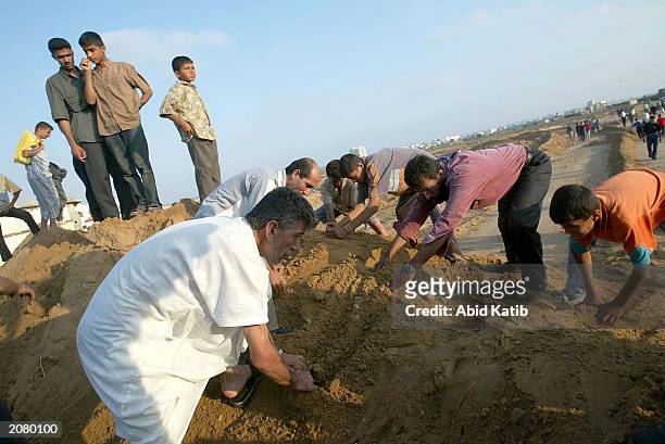 In an effort to avoid an Israeli army road block near the Netzarim Jewish settlement, Palestinians try to clear a path for a truck to cross a dirt...